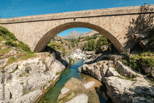 The Ponte Altu bridge at Albertacce on the Mediterranean island of Corsica passing over the crystal clear Golo river with Monte Albanu in the distance