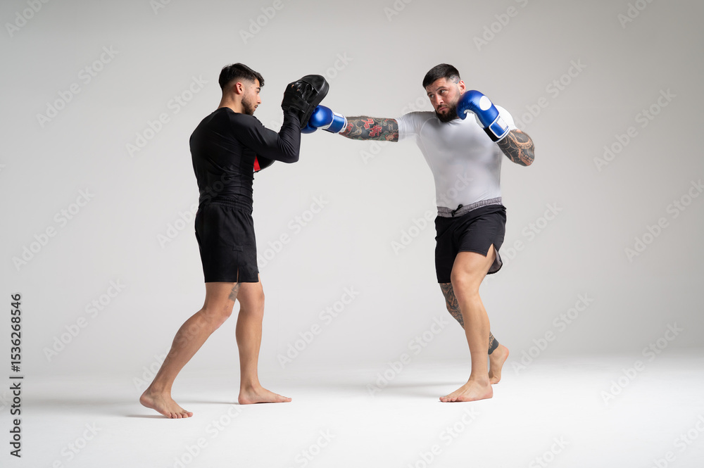 Obraz premium Two mma fighters training punches and kicks in boxing gloves