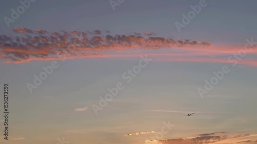 Golden sunlight bathes the landscapes and clouds in a beautiful spectrum of orange, red and blue, and in the distance a plane flies