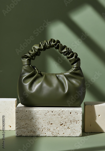 Mockup of olive green handbag on stone pedestal for fashion product branding
 photo