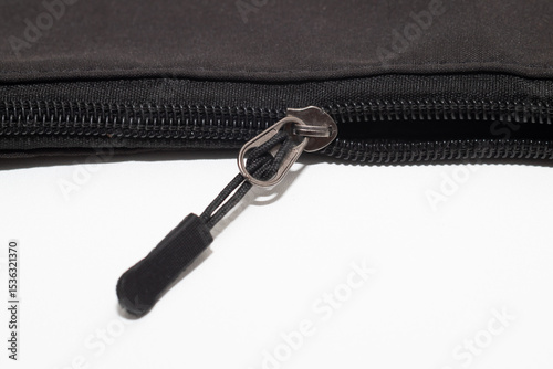 black fabric bag featuring a sleek, rubberized zipper with a metallic pull tab, set against white background.