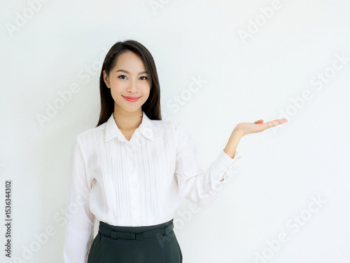 ビジネスの場で片手で「こちら」と笑顔で案内する日本人女性