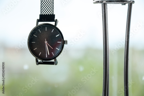 A close-up of a minimalist wristwatch in a plant-filled room, showcasing its design and the softness of natural light filtering through