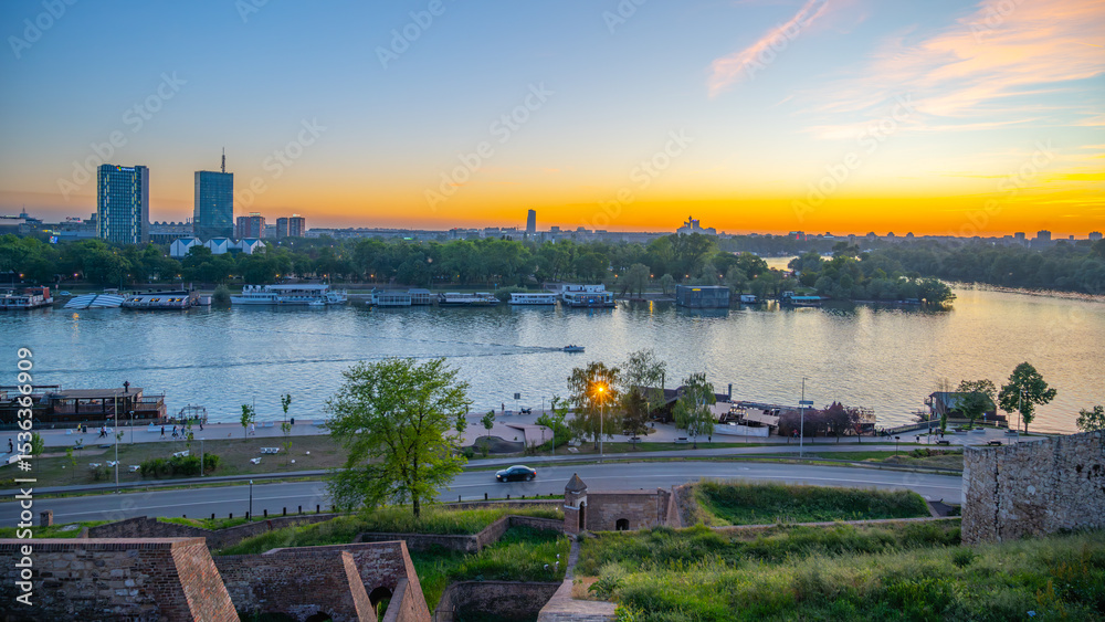 Φωτογραφία The Sava River gracefully flows past Kalamegdan fortress in Belgrade, Serbia, as the sun sets, casting vibrant colors across the sky and illuminating the tranquil water