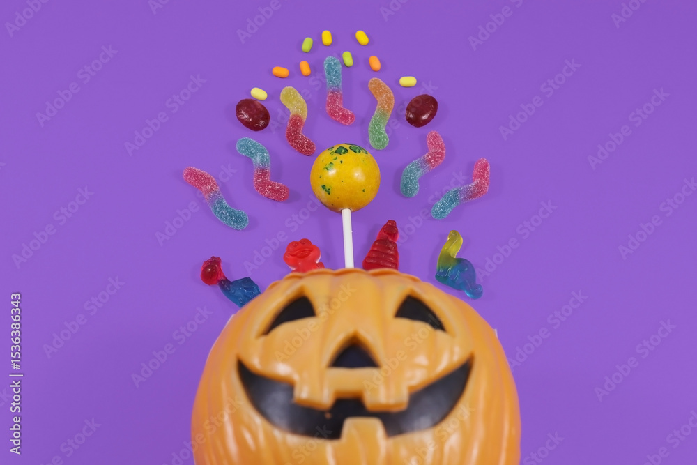 Fototapeta premium Halloween concept. Top view photo of pumpkin basket with candies purple background