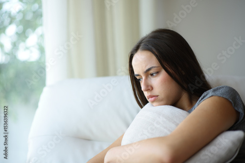 Angry woman hugging pillow at home
