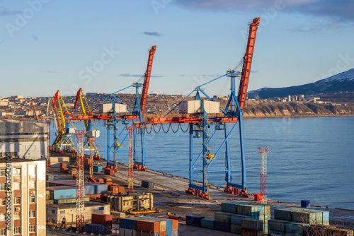 View of the port cranes and piers of the seaport. Maritime transport and port infrastructure in the Russian Far East. Nagaev Bay, Sea of Okhotsk. Magadan, Magadan Region, Russia.