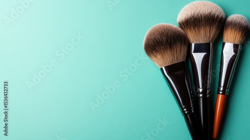 An elegant display of professional makeup brushes arranged neatly against a bright turquoise background, ideal for beauty and cosmetics branding or artistic projects.