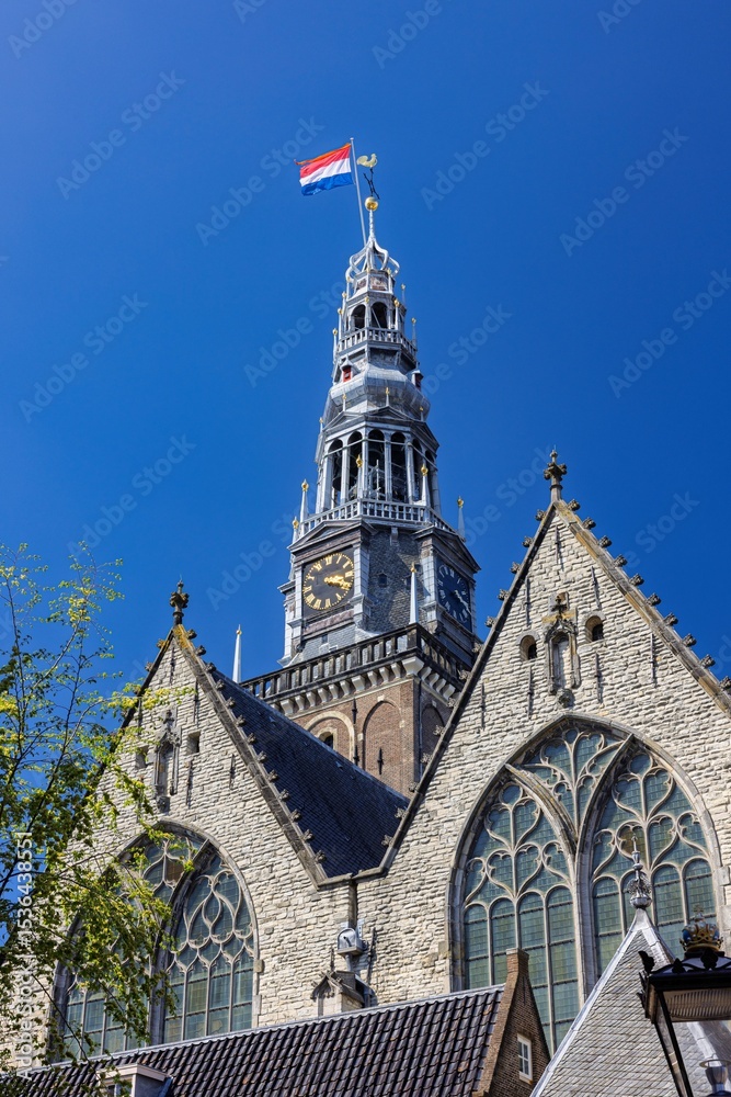 Obraz premium Oude Kerk tower with Dutch flag in Amsterdam.