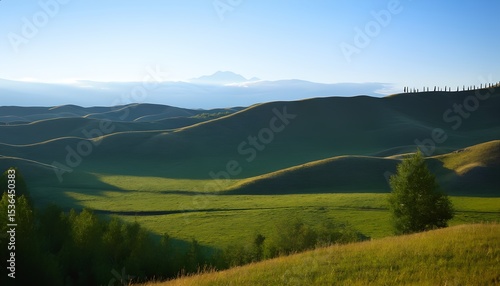 Rolling green hills with trees under a bright blue sky at sunrise