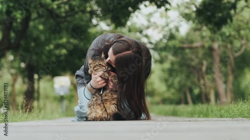 Domestic cat walking on leash with owner in summer park sunny day joyful outdoor activity pet companionship concept animal care lifestyle