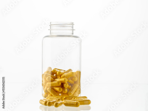 A jar of pills inside and scattered pills on a white background. Hyaluronic acid, collagen, vitamins or barberry pills to maintain beauty and lose weight. Copyspace