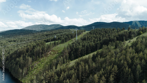 Zlatibor Grand Gondola lift crossing over lush green hills and forests in springtime. Tornik mount in spring time