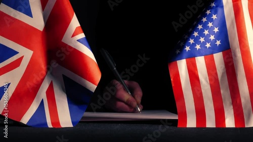 Hand signing a trade deal with American USA flag and British Union Jack