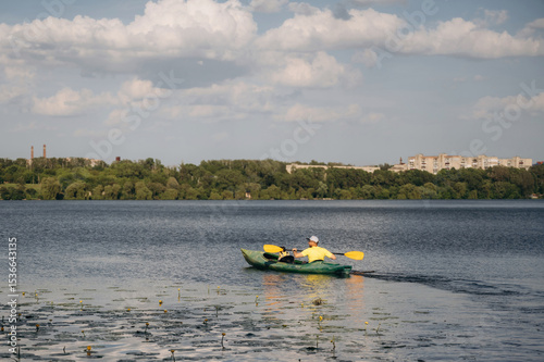 Sportive father is with his young son is swimming in the kayak