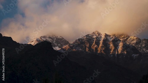 Orange clouds during the sunset above the Snowy Himalayan mountain peaks as seen from Tayul Monastery near Keylong in Lahaul Valley, Himachal Pradesh, India. Scenic sunset in the mountain peaks.