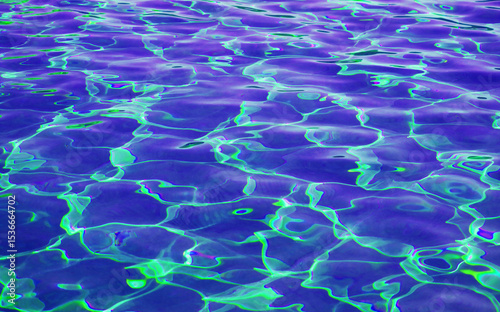 Surreal pop art of ultramarine blue and lime green colored water surface in the sunlight