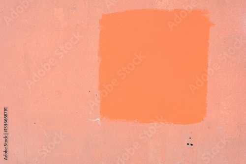  Painted patch on a wall, with an orange color applied over a lighter background.