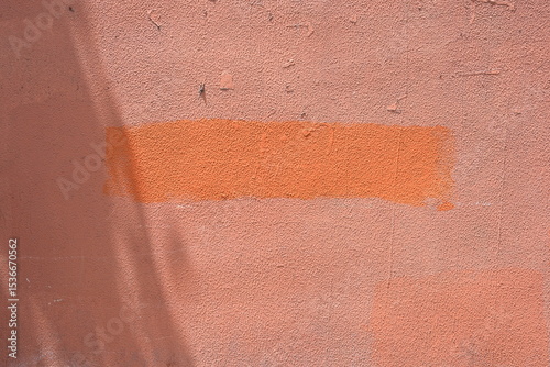  Painted patch on a wall, with an orange color applied over a lighter background.