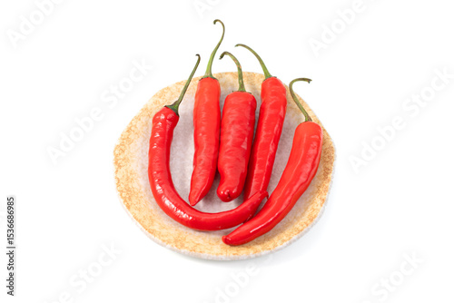 Tilted  top  view of collection of big red chili peppers placed on a handmade rustic ceramic plate, isolated on a white background photo