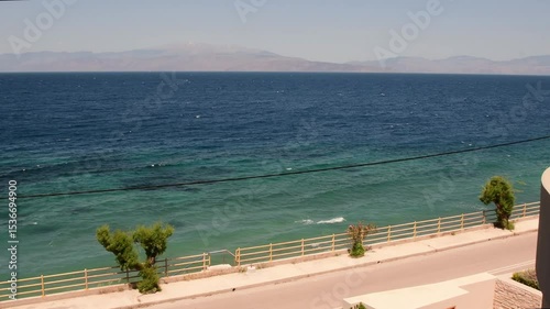 Seaside landscape showcasing serene waters and picturesque coastlines in Greece. Pan view for coastline and coastal road from balcony perfect for travelers and tourists.