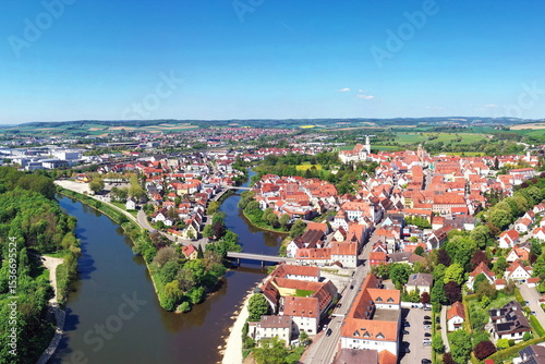 Luftaufnahme von Donauwörth mit roten Dächern, historischen Gebäuden und einem markanten Turm, eingebettet in eine grüne Landschaft. Die Stadt bietet eine charmante Kulisse.