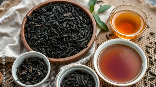 Black tea oxidizing on cloth with bowls of loose leaves and brewed tea