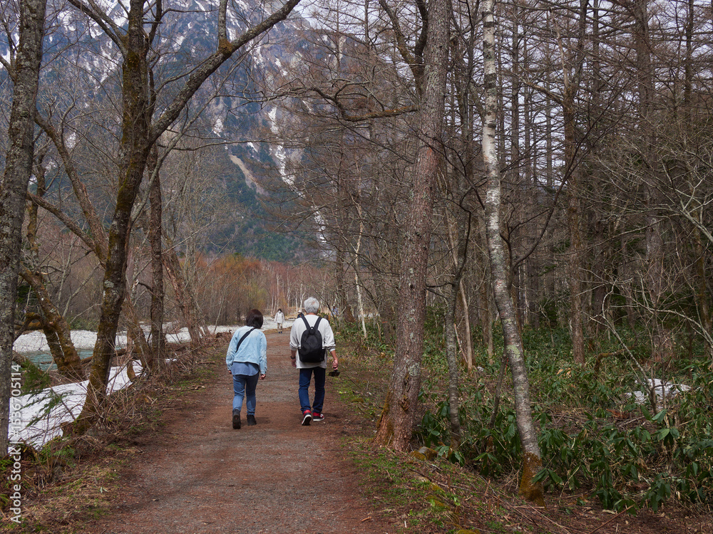 Obraz premium 初夏の観光名所上高地の穂高連峰と梓川の風景と散歩する観光客の姿