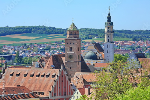 Luftaufnahme von Donauwörth mit roten Dächern, historischen Gebäuden und einem markanten Turm, eingebettet in eine grüne Landschaft. Die Stadt bietet eine charmante Kulisse.