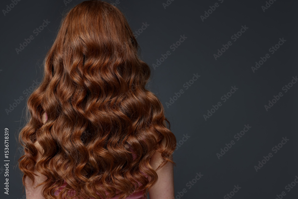 Fototapeta premium Teenage girl with healthy wavy hair on dark grey background, back view. Space for text