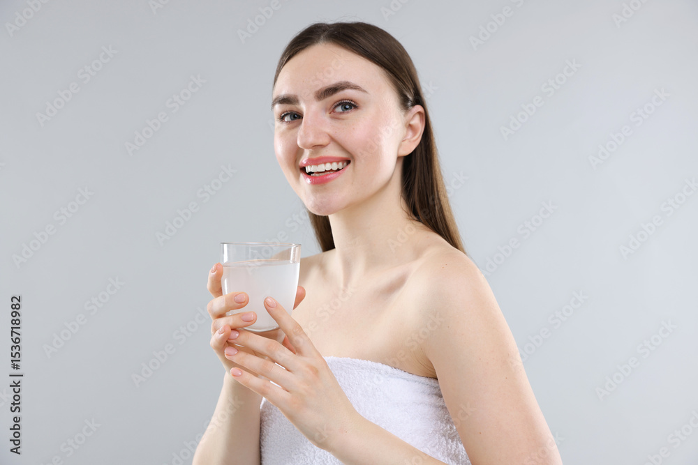 Happy woman with glass of collagen water on grey background Happy woman with glass of collagen water on grey background