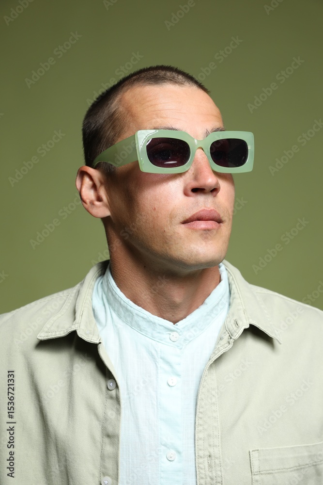 Obraz premium Fashionable portrait of handsome man in stylish outfit on green background
