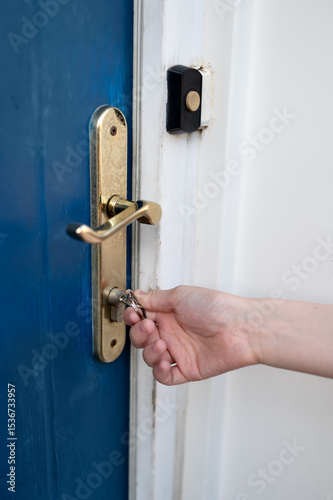 Close up a person unlocking a front door using a key. 