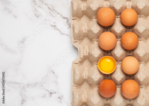 Egg box with an open egg on a white marble counter.