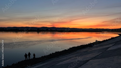 sunset over the river. people on the riverbank embankment