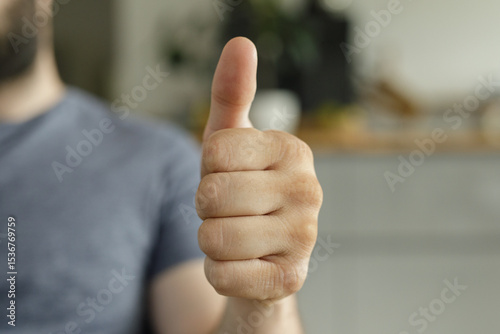 Close-up of a man's hand showing a thumbs up. Positive, approval, success.