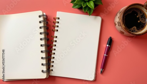 Blank Notebook and Pen with Coffee and Potted Plant on a Vibrant Coral Desk Surface