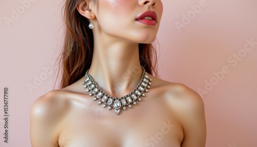 Elegant Woman Showcasing a Stunning Silver Necklace Against a Soft Pink Background