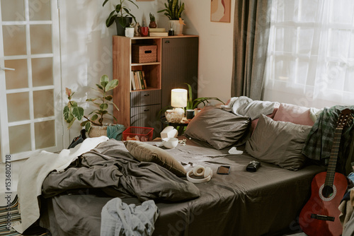 Obraz na płótnie Bedroom featuring a messy bed with cozy pillows and blankets, surrounded by vari