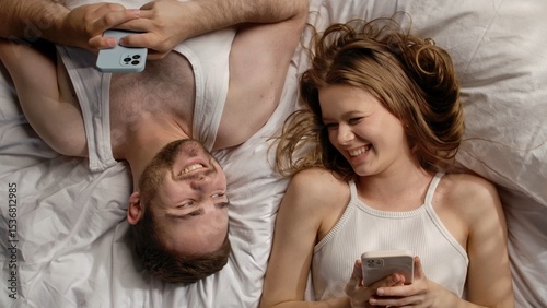 Joyful Couple Relaxing Together with Smartphones at Home photo