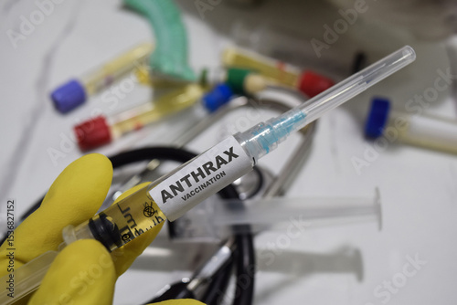 Anthrax vaccination drug syringe in yellow gloved hands. Medical concept photo