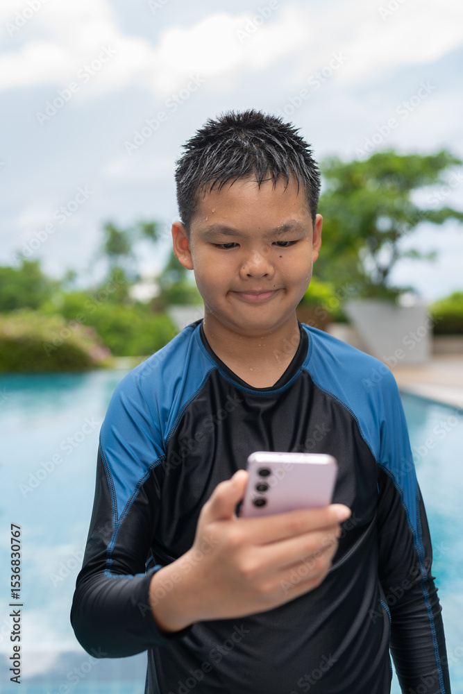 Asian teenage boy using phone after swimming in pool Asian teenage boy using phone after swimming in pool