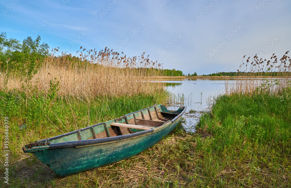 Obraz premium Weathered Green Rowboat Beached on Grass