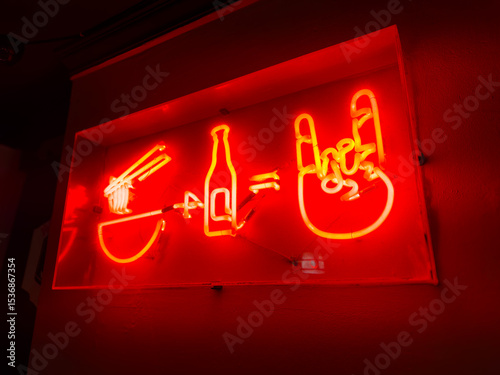 Bright red neon sign featuring a bowl of ramen, a beer bottle, and a rock hand gesture, perfect for modern Asian restaurants or nightlife-themed marketing visuals.