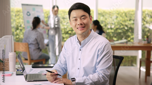 The way forward save the planet earth Gen Z male asia people go green growth net zero waste ESG office desk. Portrait headshot face young adult man asian SDGs auditor work look at camera smile happy.