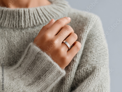 Health and wellness tracker ring displayed on hand while wearing cozy sweater, emphasizing modern fitness technology