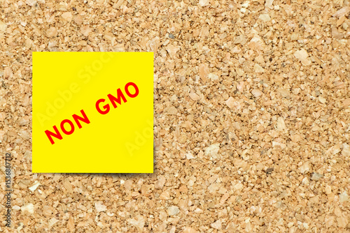Yellow note paper with word Non GMO (Genetically Modified Organisms) on cork board background with copy space