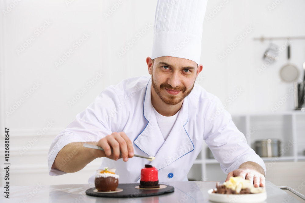 Confectioner decorating delicious dessert with chocolate shaving at table in kitchen Confectioner decorating delicious dessert with chocolate shaving at table in kitchen