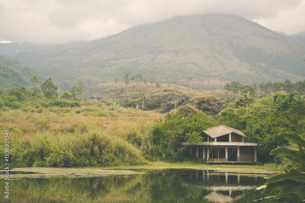 Fototapeta premium Scenic lakeside house beneath foggy mountains