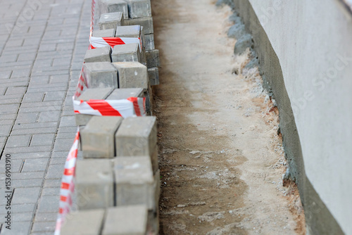 Foundation upgrade on aged building with paving removed and hydro insulation applied to prevent water penetration and heat loss. Stacked in row removed paving slabs, selective focus